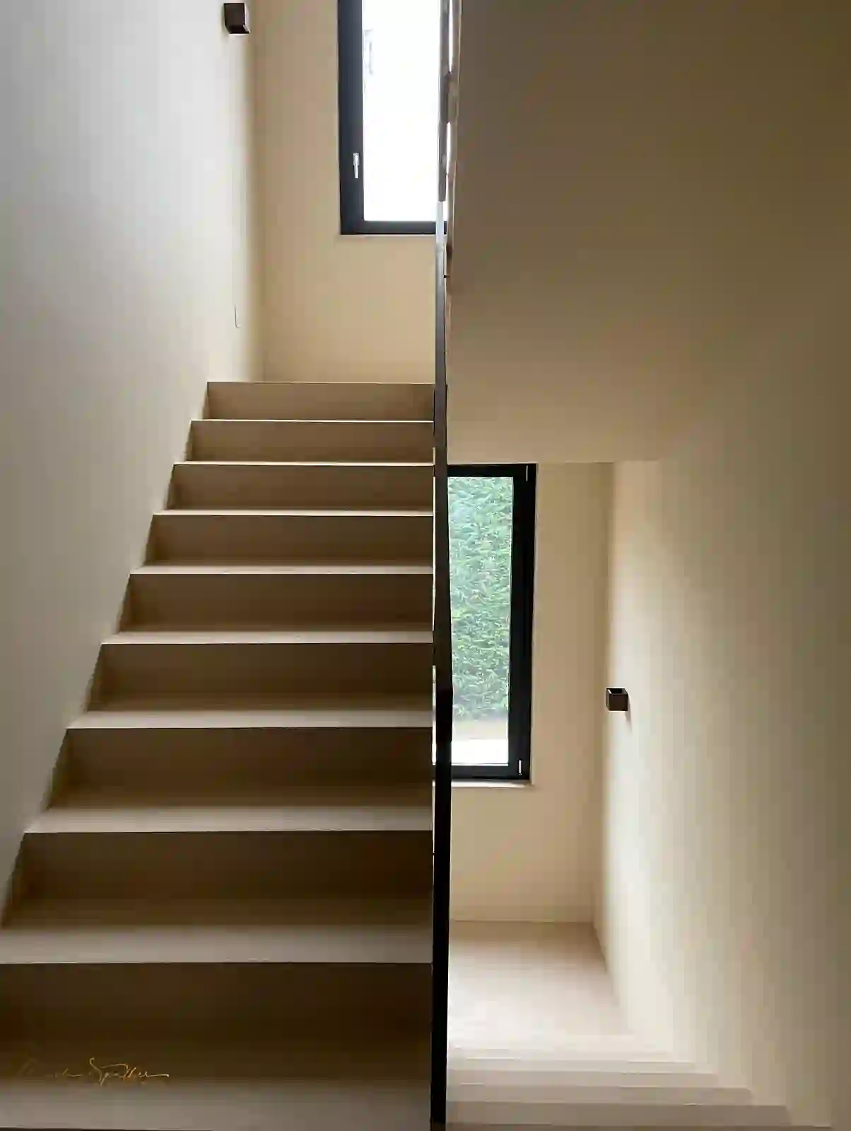 Scala chiara tra pareti neutre con finestre verticali
