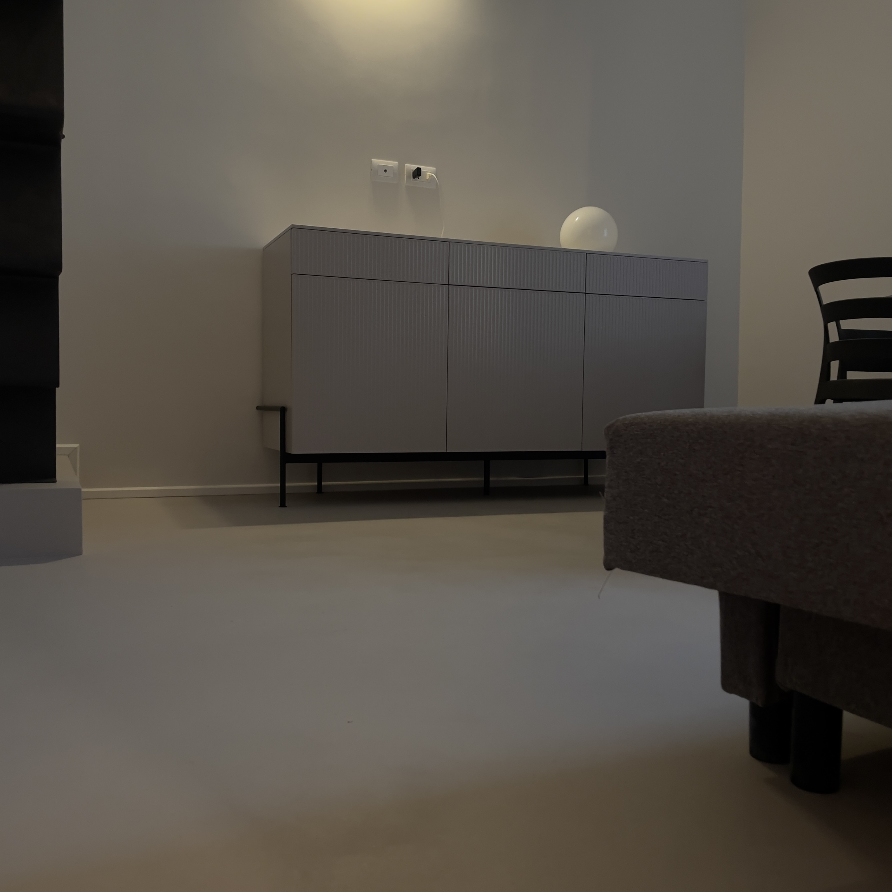 Soggiorno con pavimento continuo chiaro, credenza grigia e divano in primo piano