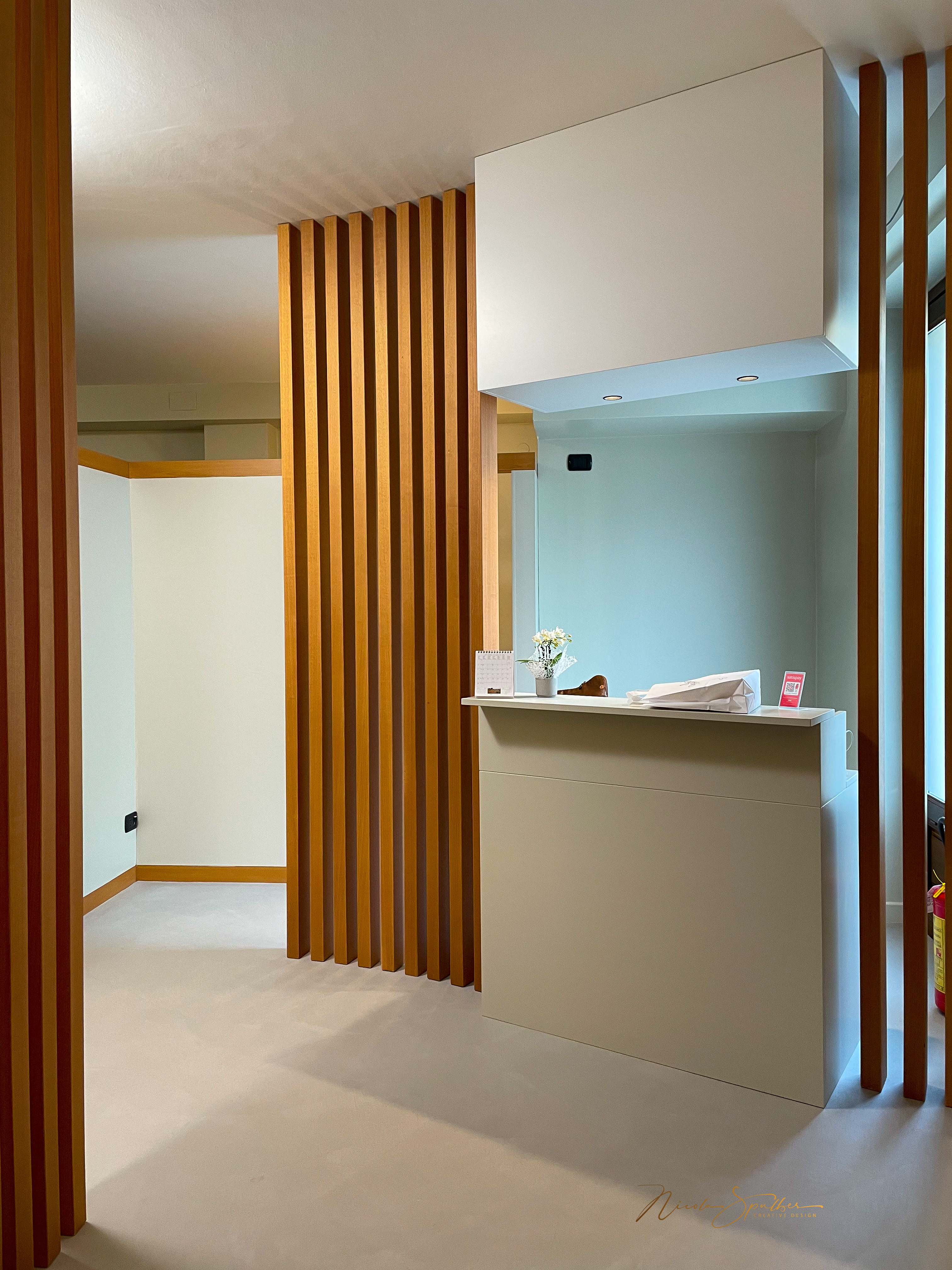 Ingresso con bancone, listelli verticali e pavimento chiaro